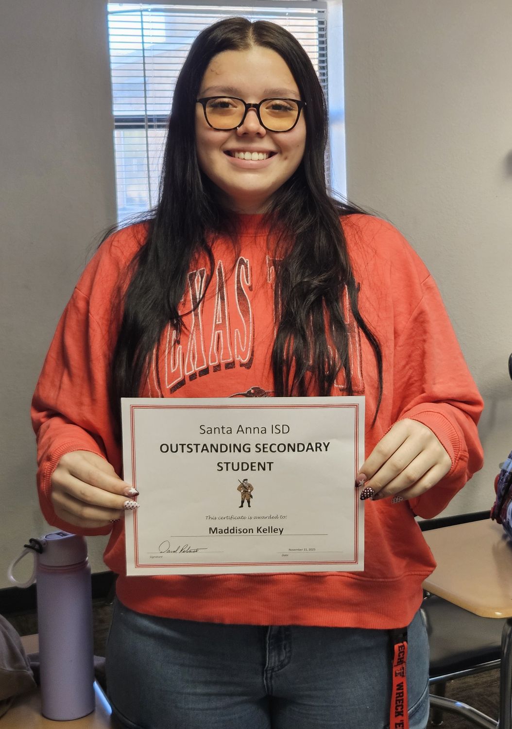 young girl in orange top holding certificate